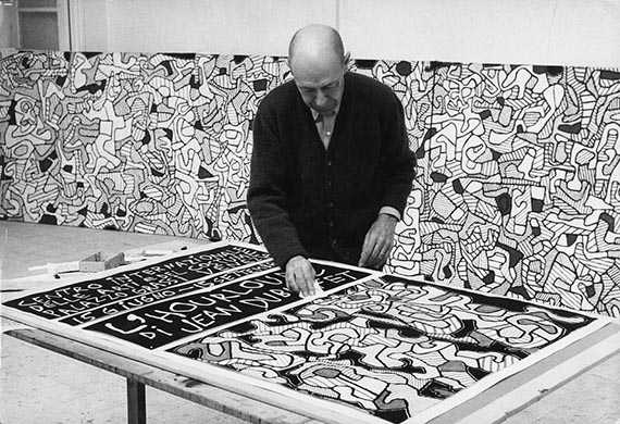 Illustration  for: Jean Dubuffet in his studio in Vence, 1964, with the oster of the “L'Hourloupe”-exhibition at Palazzo Grassi, Venice, photo: Max Loreau. © Archives Fondation Dubuffet, Paris / © VG Bild-Kunst, Bonn 2025.